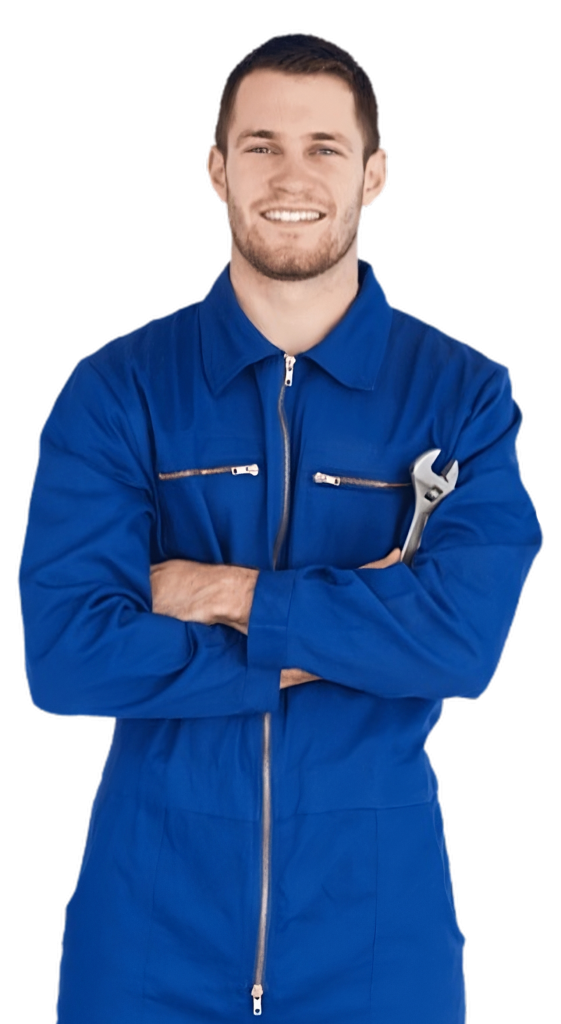 A man in blue overalls posing with crossed arms at home.